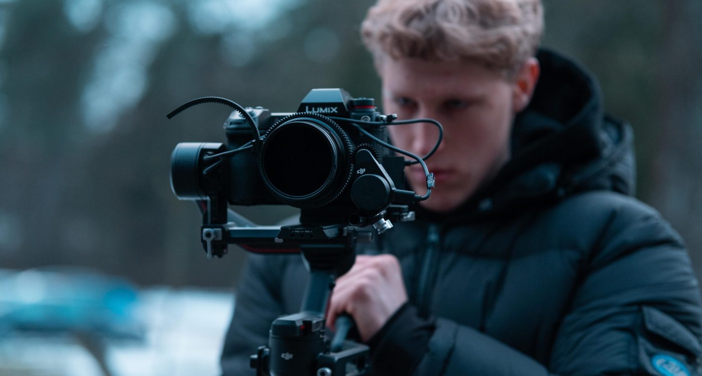 Operator filmowy w kurtce zimowej z kamerą – nagranie plenerowe